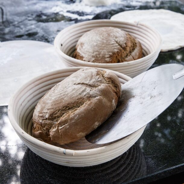 „Brotteig im runden Gärkörbchen, daneben Backschaufel – bereit für den Ofen.“