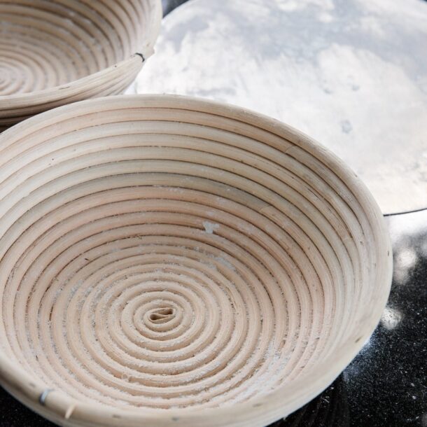 „Mit Mehl bestäubtes, rundes Gärkörbchen aus Peddigrohr in Nahaufnahme.“