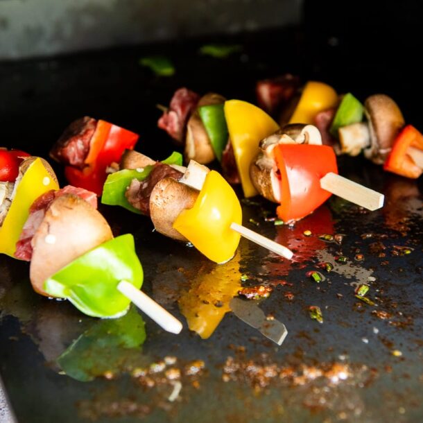 Gemüsespieße mit Paprika, Pilzen und Fleischwürfeln auf der Plancha im Holzbackofen
