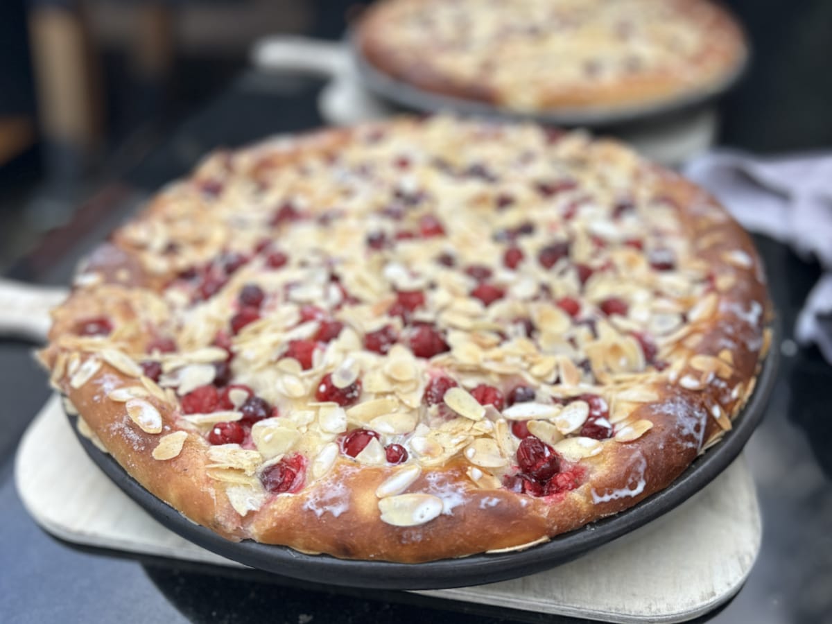 Saftiger Butterkuchen mit Cranberrys, frisch gebacken in einer runden Ofenform, im Vordergrund leicht glasiert.